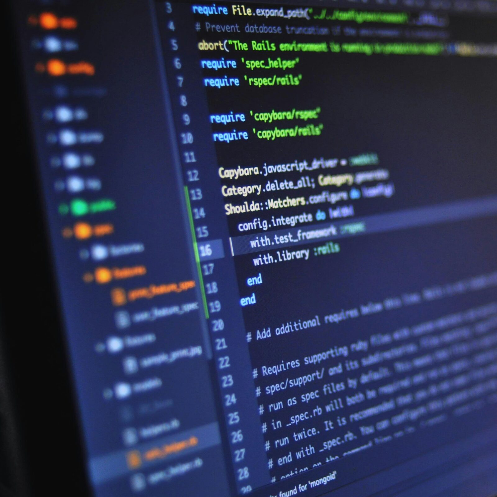 Close-up of a computer screen displaying programming code in a dark environment.
